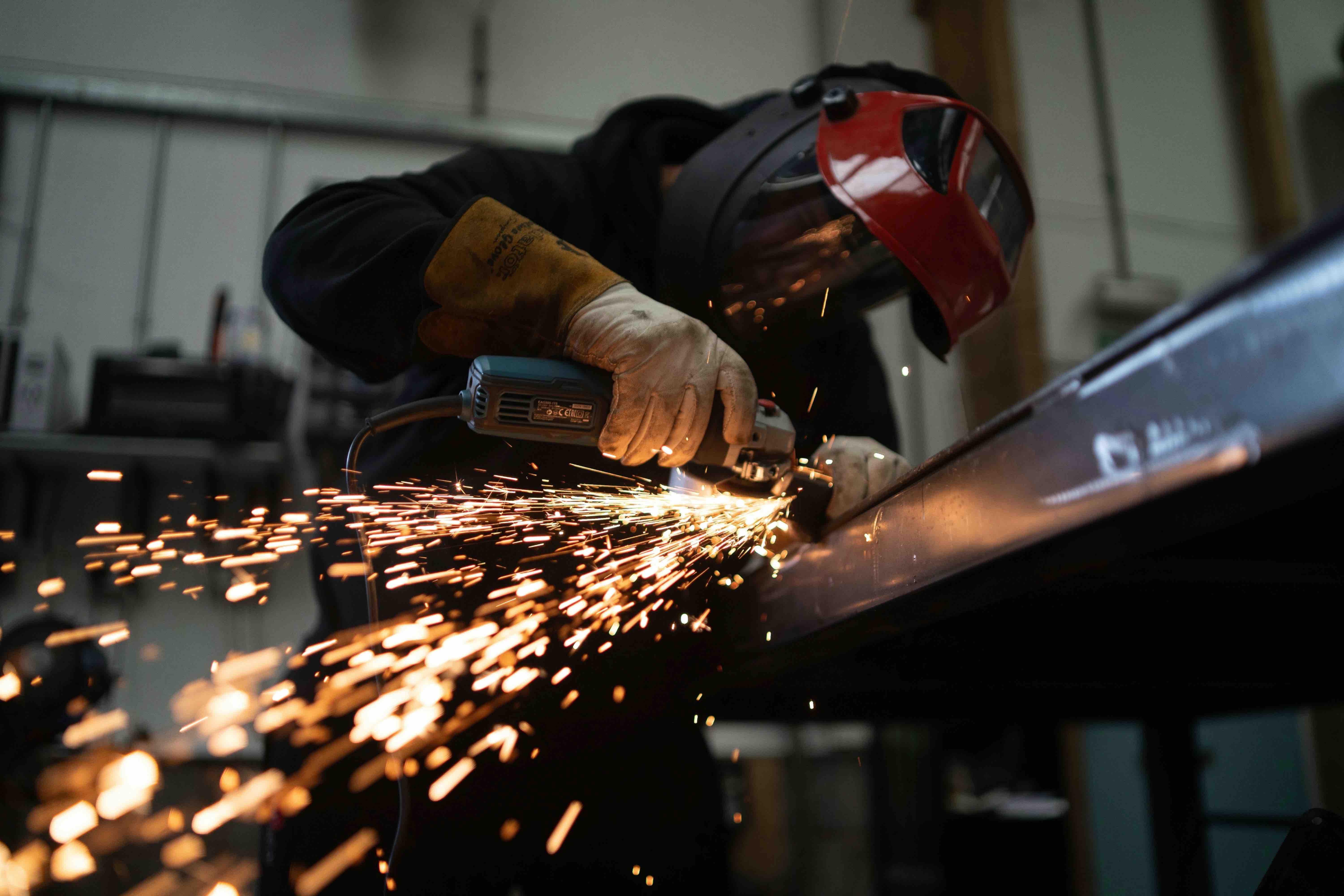 individual cutting into metal material, with sparks flying off the tool